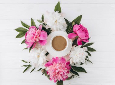 Bir fincan kahvenin etrafında pembe ve beyaz şakayıkların çiçek aranjmanı, düzlük, üst manzara