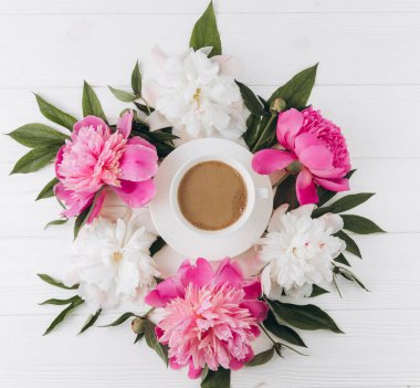 Bir fincan kahvenin etrafında pembe ve beyaz şakayıkların çiçek aranjmanı, düzlük, üst manzara