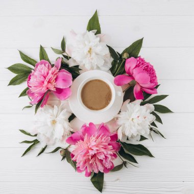 Bir fincan kahvenin etrafında pembe ve beyaz şakayıkların çiçek aranjmanı, düzlük, üst manzara