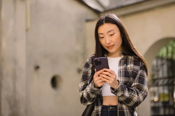 旧市街の通りに美しい韓国人女性の肖像画 携帯電話で話すカジュアルな服でアジアの女性 近代的な技術とライフスタイル — ストック写真