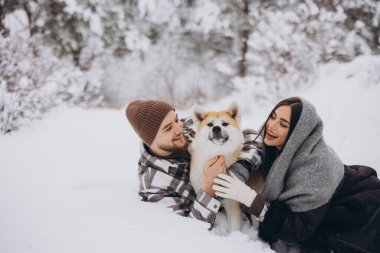 Mutlu genç çift ve akita köpeği kış günü ormanda