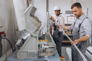 Uluslararası bir ekip, iki işçi PVC pencere ve kapı fabrikasında çalışıyor.