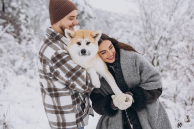 Mutlu genç çift ve akita köpek ormanda kışın ve karlı günde