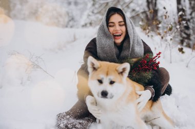 Tatlı, mutlu kadın kışın karlı ormanda Akia Inu köpeğiyle vakit geçiriyor.