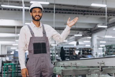 Makine operatörü. Endüstriyel Hintli uluslararası işçi fabrikadaki fotokopi alanında bir şey gösteriyor. Beyaz şapkalı genç teknisyen..