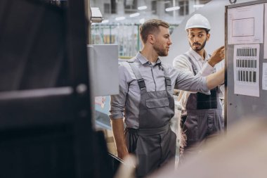 Deneyimli mühendisler üretim fabrikasında modern endüstriyel üretim makinesine hizmet veriyorlar.