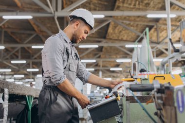 Fabrika erkek sakallı işçi bir CNC değirmen makinesini kopyalama alanı ile programlıyor..