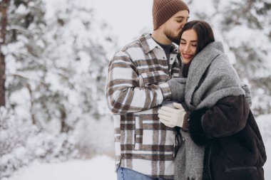 Mutlu çift dinleniyor ve ormanda sıcak çay içiyor. Kışın dağlarda.
