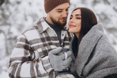 Mutlu çift dinleniyor ve ormanda sıcak çay içiyor. Kışın dağlarda.