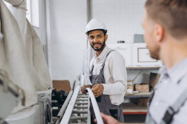 Uluslararası bir ekip, iki işçi PVC pencere ve kapı fabrikasında çalışıyor.