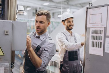 Deneyimli mühendisler üretim fabrikasında modern endüstriyel üretim makinesine hizmet veriyorlar.