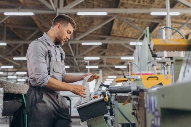 Fabrika erkek sakallı işçi bir CNC değirmen makinesini kopyalama alanı ile programlıyor..