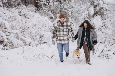 Mutlu genç çift ve akita köpek ormanda kışın ve karlı günde