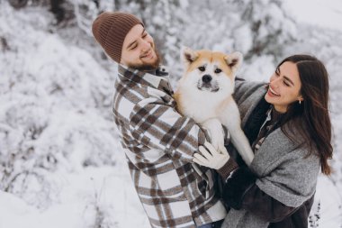 Mutlu genç çift ve akita köpeği kış günü ormanda