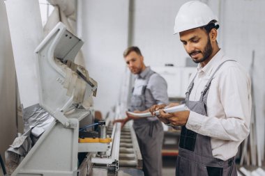 Uluslararası bir ekip, iki işçi PVC pencere ve kapı fabrikasında çalışıyor.