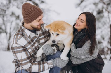 Mutlu genç çift ve akita köpek ormanda kışın ve karlı günde