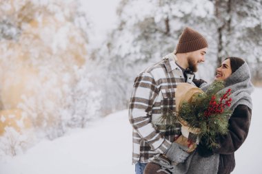 Çam buketine aşık sevimli genç çift Sevgililer Günü 'nde dağlardaki karlı kış ormanlarında vakit geçiriyor.