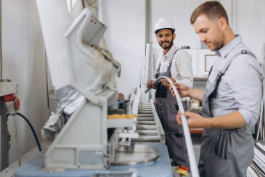 Uluslararası bir ekip, iki işçi PVC pencere ve kapı fabrikasında çalışıyor.