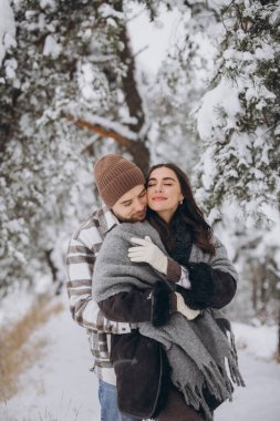 Karlı bir ormanda eğlenen mutlu ve sevgi dolu genç bir çiftin portresi.