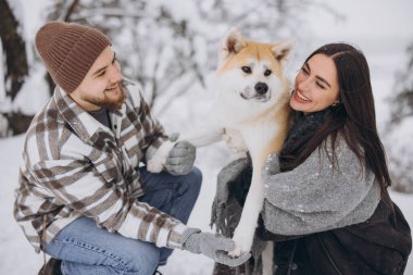 Mutlu genç çift ve akita köpek ormanda kışın ve karlı günde