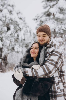 Genç ve mutlu bir çift kışın karlı bir ormanda eğleniyor..