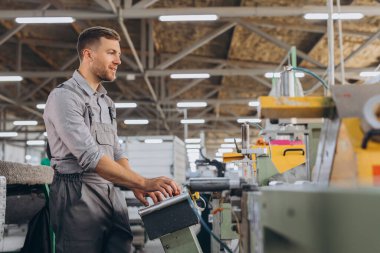 Fabrika erkek sakallı işçi bir CNC değirmen makinesini kopyalama alanı ile programlıyor..