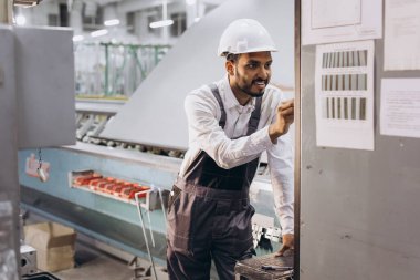 Makine operatörü. Fabrikada sanayi işçisi. Beyaz şapkalı genç teknisyen..