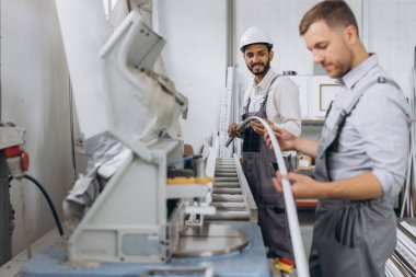 Uluslararası bir ekip, iki işçi PVC pencere ve kapı fabrikasında çalışıyor.