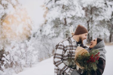 Çam buketine aşık sevimli genç çift Sevgililer Günü 'nde dağlardaki karlı kış ormanlarında vakit geçiriyor.