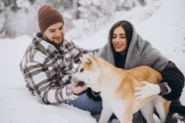 Mutlu genç çift ve akita köpeği kış günü ormanda