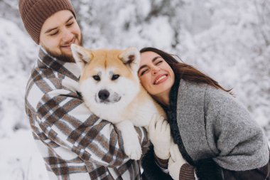 Mutlu genç çift ve akita köpek ormanda kışın ve karlı günde