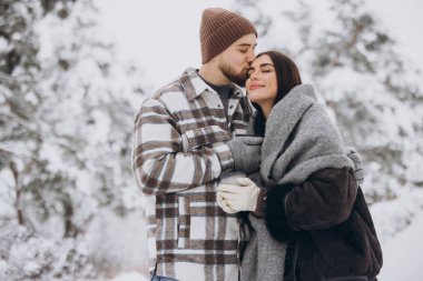 Mutlu çift dinleniyor ve ormanda sıcak çay içiyor. Kışın dağlarda.
