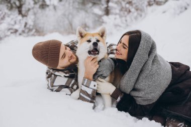 Mutlu genç çift ve akita köpeği kış günü ormanda