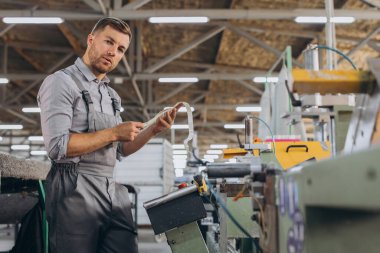 Fabrika erkek sakallı işçi bir CNC değirmen makinesini kopyalama alanı ile programlıyor..