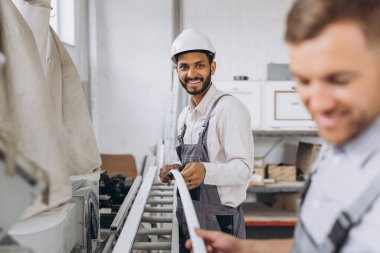 Uluslararası bir ekip, iki işçi PVC pencere ve kapı fabrikasında çalışıyor.