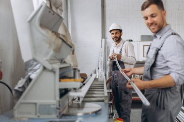 Uluslararası bir ekip, iki işçi PVC pencere ve kapı fabrikasında çalışıyor.
