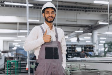 Makine operatörü. Endüstriyel Hintli uluslararası işçi fabrikada çalışıyor. Beyaz şapkalı genç teknisyen..