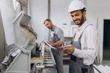 Uluslararası bir ekip, iki işçi PVC pencere ve kapı fabrikasında çalışıyor.