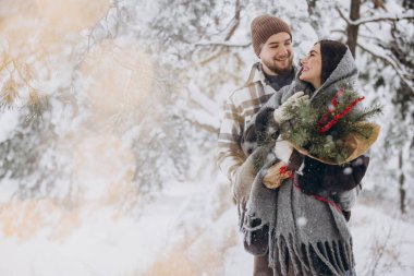 Çam buketine aşık sevimli genç çift Sevgililer Günü 'nde dağlardaki karlı kış ormanlarında vakit geçiriyor.