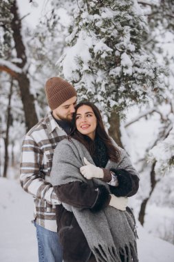 Karlı bir ormanda eğlenen mutlu ve sevgi dolu genç bir çiftin portresi.