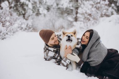 Mutlu genç çift ve akita köpeği kış günü ormanda