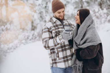 Mutlu çift dinleniyor ve ormanda sıcak çay içiyor. Kışın dağlarda.
