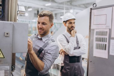 Deneyimli mühendisler üretim fabrikasında modern endüstriyel üretim makinesine hizmet veriyorlar.