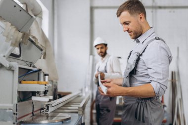 Uluslararası bir ekip, iki işçi PVC pencere ve kapı fabrikasında çalışıyor.