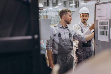 Deneyimli mühendisler üretim fabrikasında modern endüstriyel üretim makinesine hizmet veriyorlar.