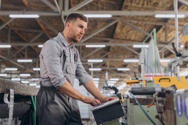 Fabrika erkek sakallı işçi bir CNC değirmen makinesini kopyalama alanı ile programlıyor..