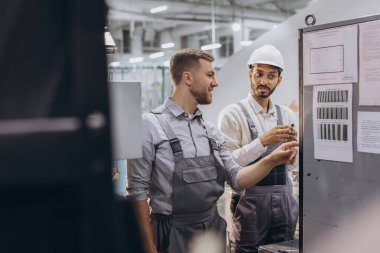 Deneyimli mühendisler üretim fabrikasında modern endüstriyel üretim makinesine hizmet veriyorlar.