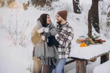 Mutlu çift dinleniyor ve ormanda sıcak çay içiyor. Kışın dağlarda.