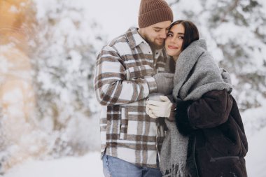 Mutlu çift dinleniyor ve ormanda sıcak çay içiyor. Kışın dağlarda.