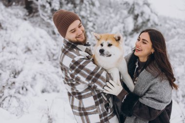 Mutlu genç çift ve akita köpeği kış günü ormanda